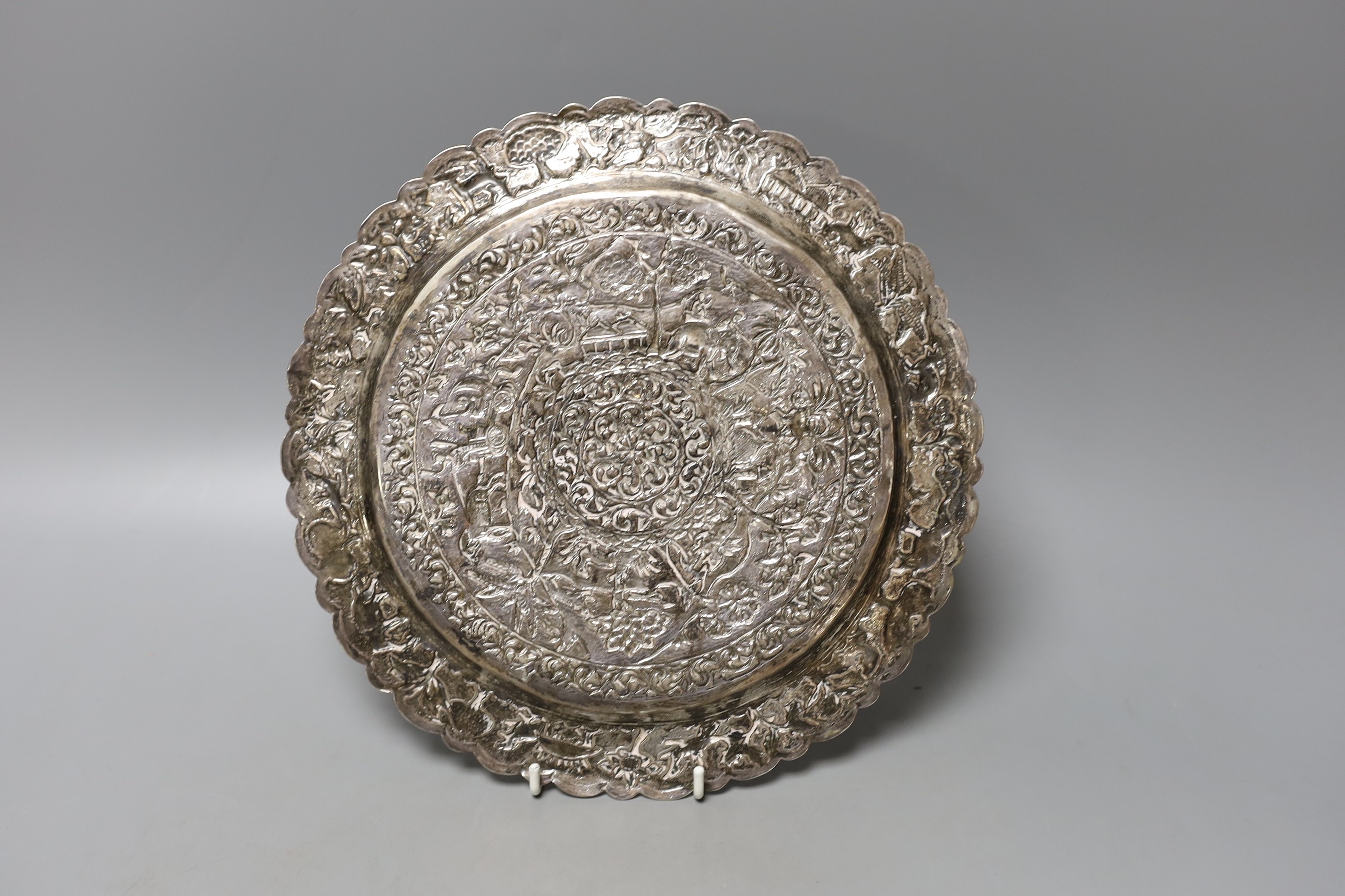 A Indian embossed white metal shallow dish, decorated with animals and foliage amid scrolls, 25.3cm, 348 grams.